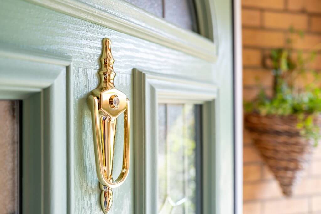 newly installed composite front door in porch. brass door knocker with an internal peephole